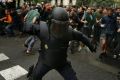 A Spanish riot police officer swings a club at would-be voters in Barcelona.