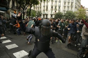 A Spanish riot police man swings a club against would-be voters near a school assigned to be a polling station by the Catalan government in Barcelona, Spain, Sunday, Oct. 1, 2017.