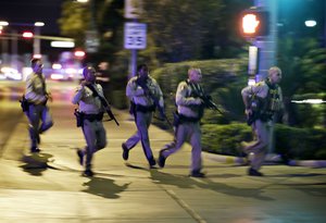 Police run to cover at the scene of a shooting near the Mandalay Bay resort and casino on the Las Vegas Strip, Sunday, Oct. 1, 2017, in Las Vegas.