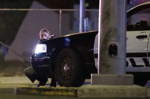 A police officer takes cover behind a police vehicle during a shooting near the Mandalay Bay resort and casino on the Las Vegas Strip, Sunday, Oct. 1, 2017, in Las Vegas.