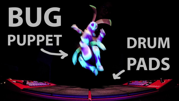 A Lively Glowing Bug Puppet Dances Upon Drum Pads That Provide Musical Accompaniment