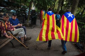 Two men watch pro independence supporters passing by as they gather in support for the secession of the Catalonia region ...