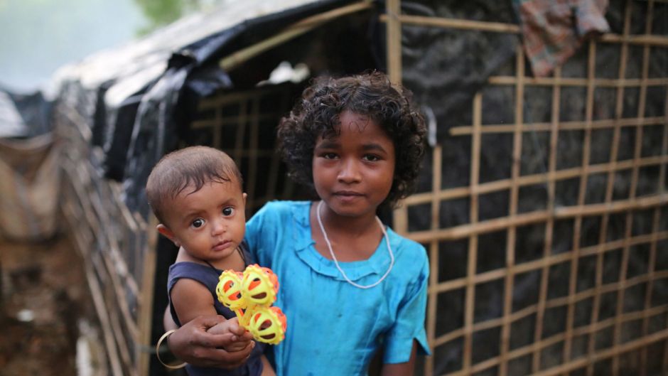 A Rohingya girl carries a child and stands for a photograph at a makeshift camp near Kutupalong refugee camp in Cox's ...