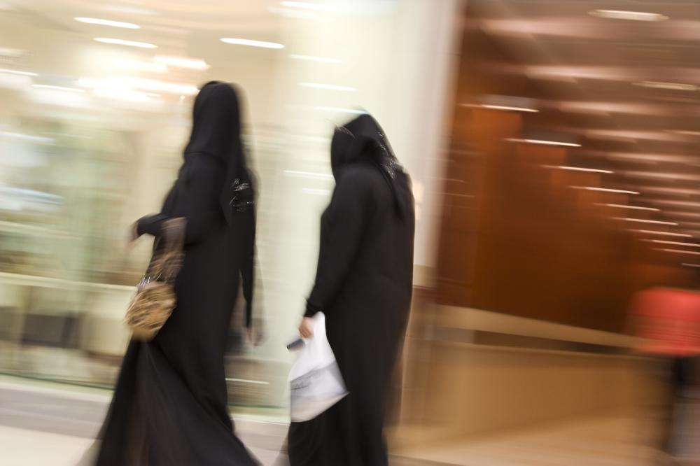 Dubai UAE Two women dressed in traditional abayas and hijabs black robes and scarves.