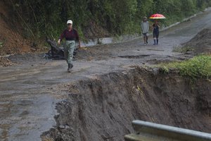 Neighbors walk under the rain past a washed out road in Alajuelita on the outskirts of San Jose, Costa Rica, Thursday, Oct. 5, 2017. Tropical Storm Nate formed off the coast of Nicaragua on Thursday and was being blamed for at least 22 deaths in Central America