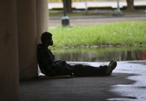 A homeless person, sits under the Pontchartrain Expressway, as sanitation employees, not pictured, carry people's possessions to a garbage truck, during a homeless sweep in New Orleans, in advance of approaching Hurricane Nate, Saturday, Oct. 7, 2017.