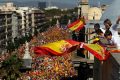 People on a rooftop wave Spanish flags during a march in downtown Barcelona, Spain, to protest the Catalan government's ...