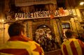 Pro independence supporters wrapped by ''esteleda'' or Catalan pro independence flags in front a balcony with a banner ...