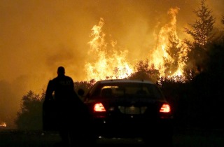 A police officer blocks a road as flames from a wildfire threaten a residential area in Santa Rosa, north of San Francisco. 