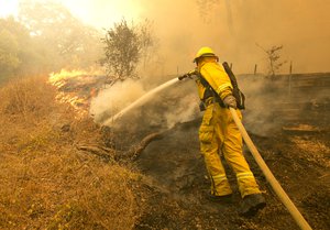 Napa County firefighter James George hoses down a fireline approaching a home Monday, Oct. 9, 2017, in Napa, Calif.