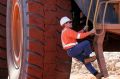 A worker climbs a ladder to enter the cab of a large ore moving truck at the Telfer Mine in the Pilbara region of ...