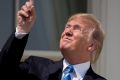 President Donald Trump points to the sun, unprotected, during the solar eclipse.