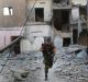 A US-backed Syrian Democratic Forces fighter runs in front of a damaged building as he crosses a street on the front ...