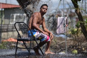 In this Sept. 29, 2017 photo, Jorge Ortiz, 25, takes a shower using well water on the side of the road in Santa Isabel, ...