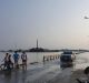 People watch a car driving on a flooded road in Hanoi.