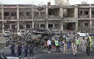 Somali security forces and others gather and search for bodies near destroyed buildings at the scene of Saturday's blast, in Mogadishu, Somalia Sunday, Oct. 15, 2017.