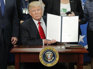 President Donald Trump holds up an executive order for border security and immigration enforcement improvements after signing the order during a visit to the Department of Homeland Security headquarters in Washington, Wednesday, Jan. 25, 2017.