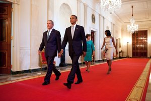 File - President Barack Obama and First Lady Michelle Obama walk with former President George W. Bush and former First Lady Laura Bush in the Cross Hall towards the East Room of the White House, May 31, 2012.