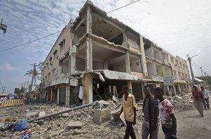 Men walk near destroyed buildings as thousands of Somalis gathered to pray at the site of the country's deadliest attack and to mourn the hundreds of victims, at the site of the attack in Mogadishu, Somalia Friday, Oct. 20, 2017.