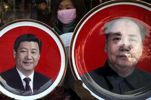 A woman looks at souvenir plates bearing images of Chinese President Xi Jinping and late Chinese leader Mao Zedong