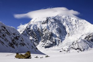 At 17,400 feet, Mount Foraker towers above soldiers as they offload equipment and supplies from a CH-47F Chinook helicopter after landing on Kahiltna Glacier in Denali National Park and Preserve, Alaska, USA