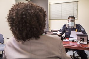 File - An Office of Field Operations Officer conducts an interview with a passenger arriving from either: Guinea, Sierra Leone, or Liberia at the at Washington Dulles International Airport during enhanced Ebola screening.