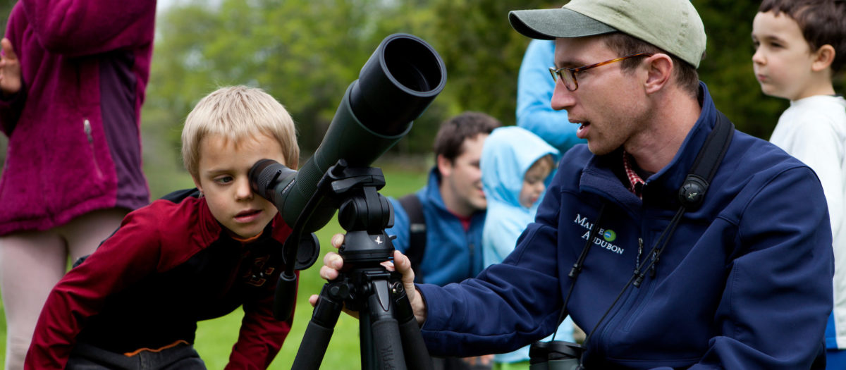 Staff Naturalist Doug Hitchcox helps a boy view wildlife through a scope