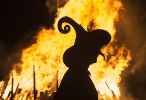 A woman dressed as a witch walks in front of a giant fire during the Walpurgis night in Erfurt, central Germany, Sunday, April 30, 2017.