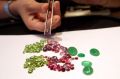 A jewellery employee displays some of Myanmar's gems: peridot, left, ruby, center, and green jade, in Yangon.