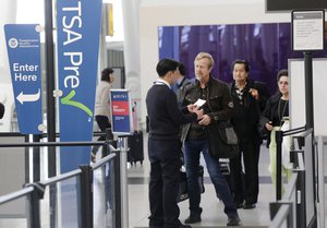 File - Travelers at John F. Kennedy International Airport are checked in by a Transportation Security Administration employee, left, at a TSA Pre line, Thursday, Oct. 30, 2014 in New York.