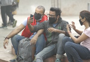 In this Thursday, Nov. 9, 2017, photo, Nikunj Pandey, left, sits with his friends wearing pollution mask in New Delhi, India