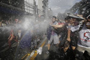 Protesters are hit by a water canon as they are dispersed by police while trying to get near the U.S. Embassy in Manila, Philippines on Sunday Nov. 12, 2017.