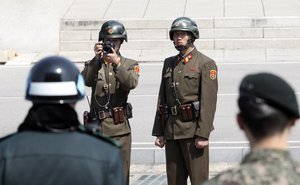 A North Korean soldier, right, looks at the south side and another soldier takes photos as two South Korean soldiers stand guard while U.S. Secretary of State Rex Tillerson visiting at the border village of Panmunjom, which has separated the two Koreas since the Korean War, South Korea, Friday, March 17, 2017.