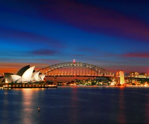 Two of Sydney's famous icons, the Sydney Opera House and Sydney Harbour Bridge lit up at dusk after a vivid sunset.