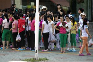 In this Sept. 2, 2017, photo, North Korean workers from the Hong Chao Zhi Yi garment factory gather for a head count after shopping at a street market in the city of Hunchun, in northeastern China's Jilin province.