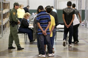 In this Wednesday, June 18, 2014 file photo, boys wait in line to make a phone call as they are joined by hundreds of mostly Central American immigrant children that are being processed and held at the U.S. Customs and Border Protection Nogales Placement Center in Nogales, Ariz.