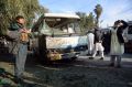 An Afghan security policeman stands guard near a damaged bus after a suicide attack in Nangarhar province east of Kabul, ...