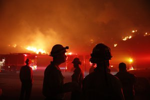 Firefighters gather in front of a residential area as a wildfire burns along the 101 Freeway Tuesday, Dec. 5, 2017, in Ventura, California.