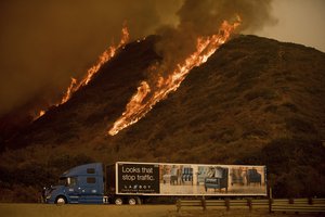 Flames from the Thomas fire burn above a truck on Highway 101 north of Ventura, California, on Wednesday, Dec. 6, 2017.