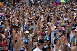 Demonstrators raise their arms in solidarity during a rally with human rights activists, in Caracas, Venezuela, Friday, Feb. 28, 2014. The start of a weeklong string of holidays leading up to the March 5 anniversary of former President Hugo Chavez's death has not completely pulled demonstrators from the streets as the government apparently hoped. President Nicolas Maduro announced this week that he was adding Thursday and Friday to the already scheduled long Carnival weekend that includes Monday and Tuesday off, and many people interpreted it as an attempt to calm tensions.