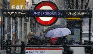 A woman walks away from Notting Hill underground station as snow falls in London