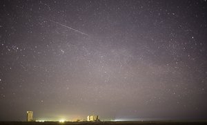 File - In this one minute exposure, a meteor streaks across the sky as the Soyuz TMA-19M spacecraft is rolled out by train to the launch pad at the Baikonur Cosmodrome on Sunday, Dec. 13, 2015 in Kazakhstan.