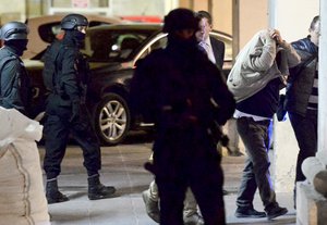 A man, right, covers his face with his jacket as he is escorted to a court in Valletta, Malta, Tuesday, Dec. 5, 2017.