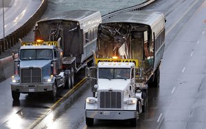 Two damaged train cars are removed atop flatbed trailers from the scene of an Amtrak train crash onto Interstate 5 a day earlier Tuesday, Dec. 19, 2017, in DuPont, Washington.