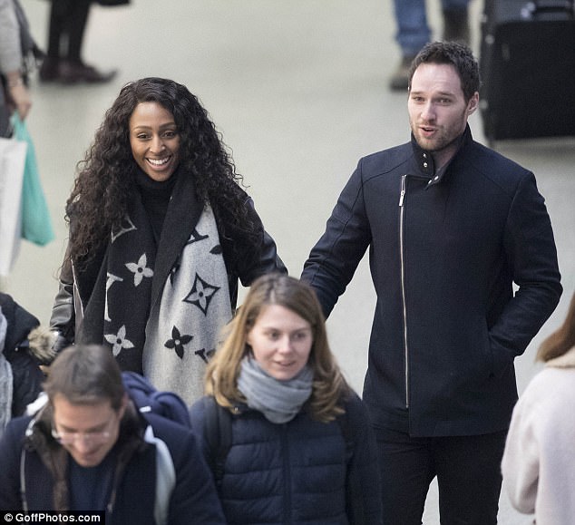 Can't contain her smiles: Alexandra Burke hid her ring finger on Monday night as she arrived back in London with boyfriend Josh Ginnelly following a whirlwind 24 hours in Paris, which prompted speculation that the stage manager had popped the question