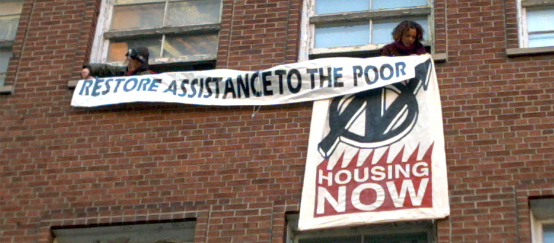 OCAP occupation of Liberal Party headquarters to demand a raise in the rates. Banners being hung outside the windows say "Restore assistance to the poor" and "housing now"