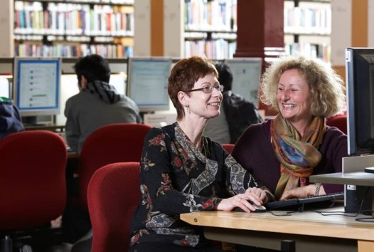 Colour photo of two women using a computer in the Redmond Barry Reading Room, State Library Victoria