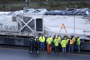 State Patrol officers and workers gather before transporting the engine from an Amtrak train crash two days earlier away from the scene, Wednesday, Dec. 20, 2017, in DuPont, Washington.