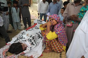 FILE - In this file picture taken on July 18, 2016, the mother of Pakistan's slain social media star Qandeel Baloch mourns besides her dead body in Shah Sadderuddin, Pakistan. Baloch grew up in a poor farming family but “always wanted more, had different ideas” her sister says.