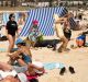 A woman stumbles on a long guide rope on a crowded Bondi Beach in Sydney